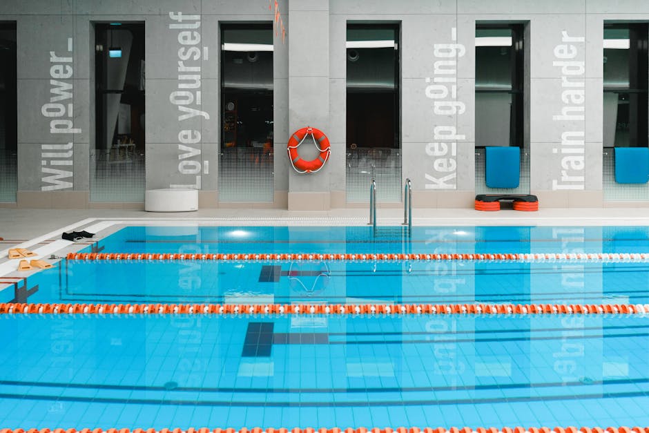 A modern indoor swimming pool with motivational quotes on the walls and clear water.