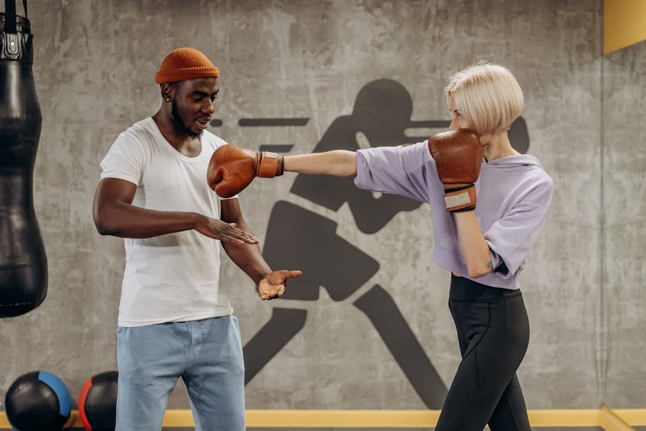 A female boxer in gloves trains with a coach in an indoor gym, focusing on technique.