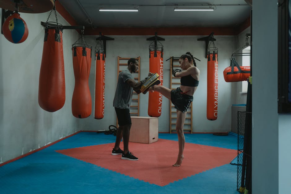 Two adults engaged in an intense kickboxing training session in a well-equipped gym.